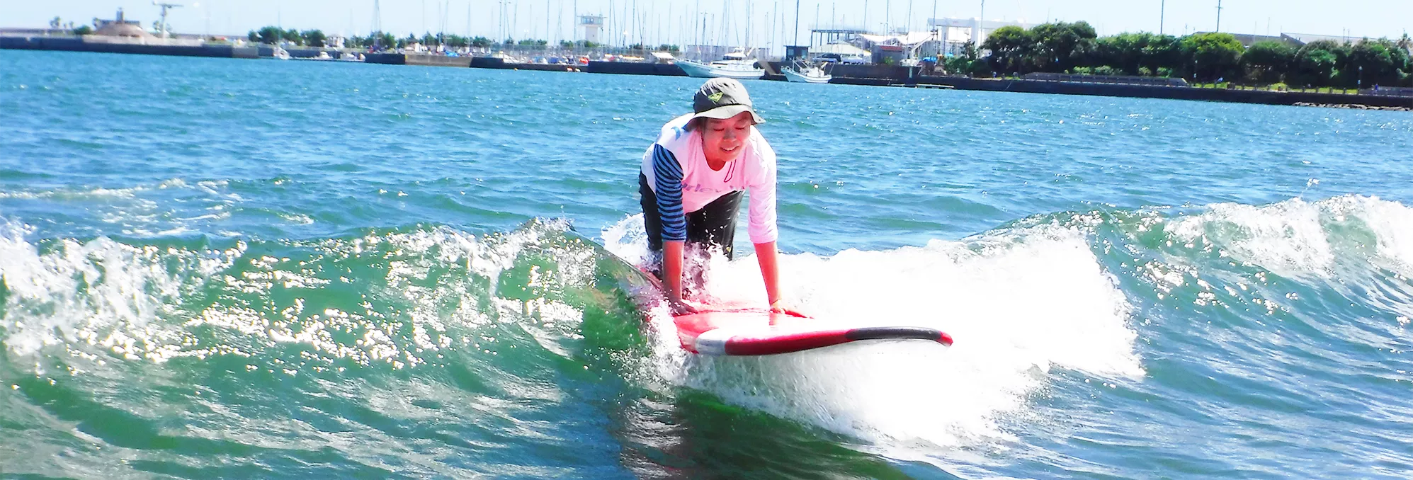 湘南の穏やかな波でリラックスしながらサーフィンを楽しむ女性のイメージ